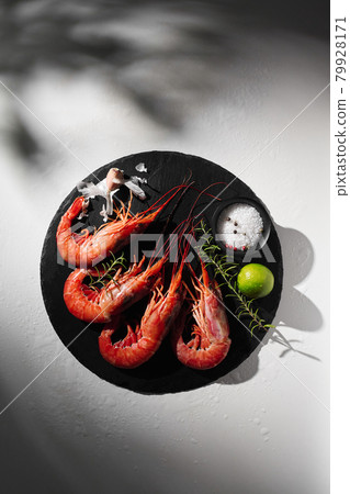 Whole prawns on round slate board with condiments, lime, garlic and rosemary Whole prawns on round slate board with condiments, lime, garlic and rosemary 79928171