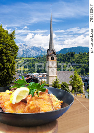 Traditional Austrian gastronomy( Schnitzel) against Bischofshofen with castle in Austria Traditional Austrian gastronomy( Schnitzel) against Bischofshofen with castle in Austria 79928867