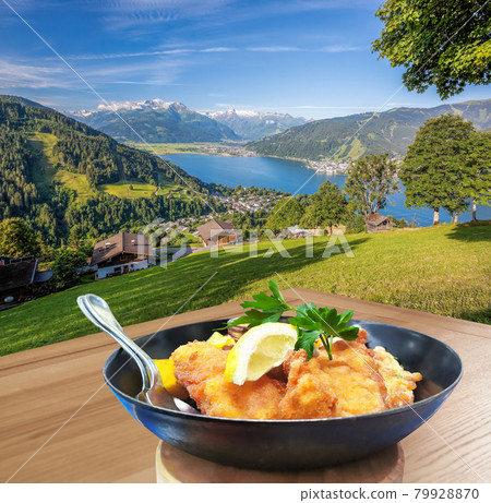 Traditional austrian food (Wiener schnitzel) against Zell am see village with lake in Austria Traditional austrian food (Wiener schnitzel) against Zell am see village with lake in Austria 79928870
