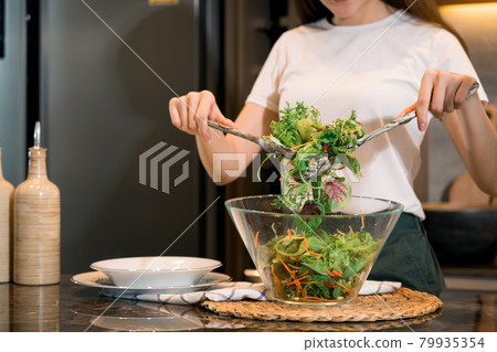 Asian housewife preparing fresh vegetables to make salad at home kitchen counter. Asian housewife preparing fresh vegetables to make salad at home kitchen counter. 79935354