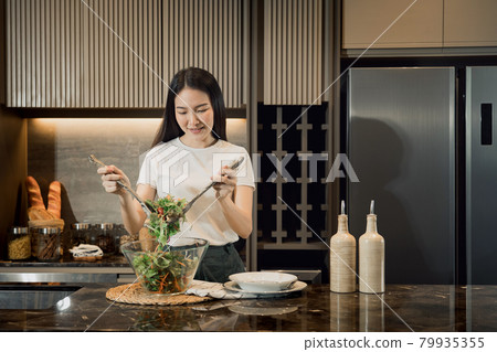 Asian housewife preparing fresh vegetables to make salad at home kitchen counter. Asian housewife preparing fresh vegetables to make salad at home kitchen counter. 79935355