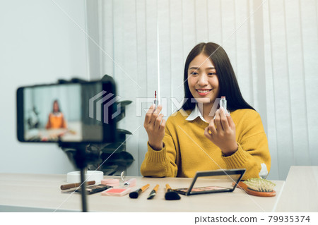 Young Asian beauty blogger is showcasing cosmetic products as well as tutorials on how to apply and record makeup tutorials on social media networks. Young Asian beauty blogger is showcasing cosmetic products as well as tutorials on how to apply and record makeup tutorials on social media networks. 79935374