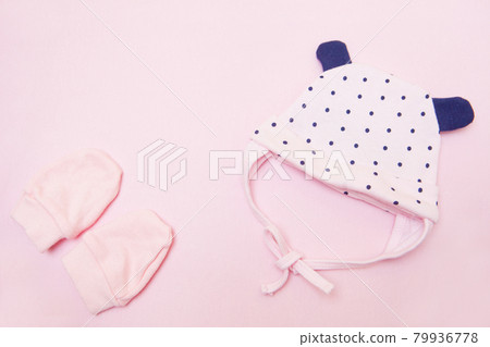 pink baby coif and mittens. Clothes for little girl on pink background top view pink baby coif and mittens. Clothes for little girl on pink background top view 79936778