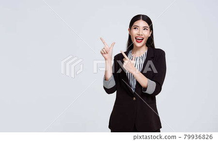 Happy Confident Asian business woman pointing finger on blank space beside isolated on gray background.. 79936826