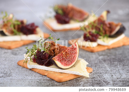 Cracker with a slice of camembert with confiture and figs 79948689