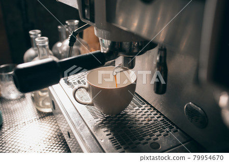Fresh aromatic hot coffee flows from the coffee machine into a white cup. Close up image 79954670