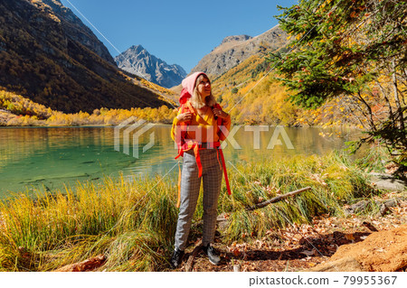Happy woman with backpack at lake in the autumnal mountains. Mountain lake and tourist Happy woman with backpack at lake in the autumnal mountains. Mountain lake and tourist 79955367
