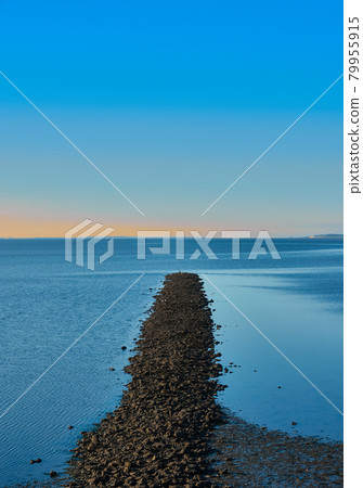 Breakwater made of gravel stones in the blue North Sea against a blue sky, abstract, calm, meditative 79955915