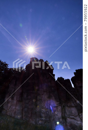 Bright midday sun behind a bizarre sandstone formation near Detmold, Germany, Externsteine Bright midday sun behind a bizarre sandstone formation near Detmold, Germany, Externsteine 79955922