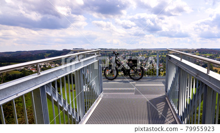 Skywalk made of gratings with an electric bicycle parked on the front railing during a bicycle tour Skywalk made of gratings with an electric bicycle parked on the front railing during a bicycle tour 79955923