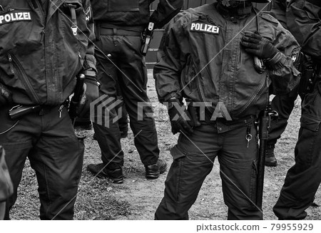 Policemen in black uniforms with pistols, handcuffs and batons, black and white, inscription Pollizei translates Police Policemen in black uniforms with pistols, handcuffs and batons, black and white, inscription Pollizei translates Police 79955929