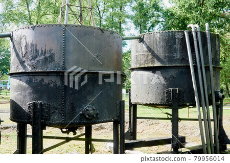 Storage tank for produced oil next to an oil well Storage tank for produced oil next to an oil well 79956014