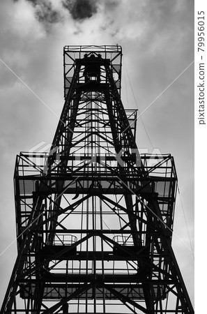 silhouette of a drilling tower for crude oil in front of a cloudy sky, black and white silhouette of a drilling tower for crude oil in front of a cloudy sky, black and white 79956015