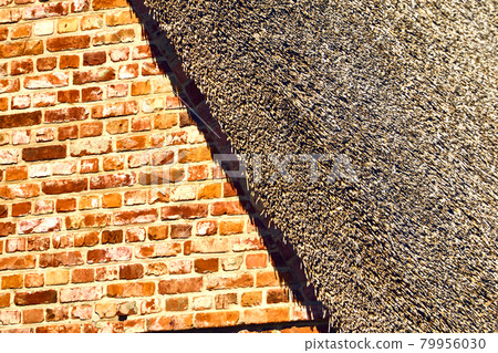Abstract looking part of a brick house with a thatched roof in the hard midday sun 79956030