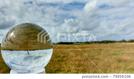Crystal ball with the flat landscape of the North Sea island Sylt with a lighthouse Crystal ball with the flat landscape of the North Sea island Sylt with a lighthouse 79956106