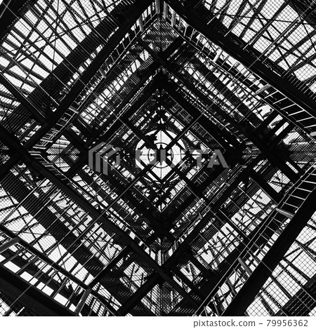 Viewing tower constructed from gratings, photographed vertically from below, abstract and black and white with hard contrast 79956362