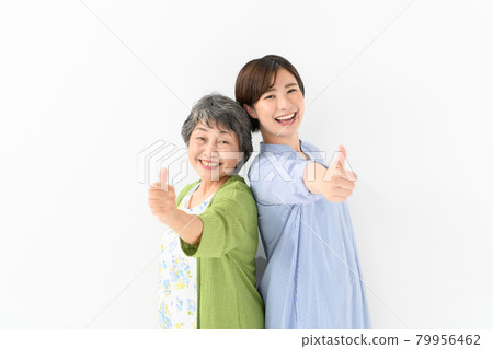 Senior woman, young woman, smile, thumbs up Senior woman, young woman, smile, thumbs up 79956462