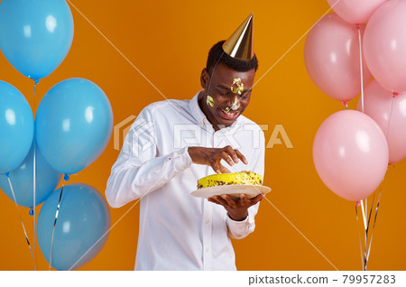 Man in cap with smeared face tasting birthday cake 79957283