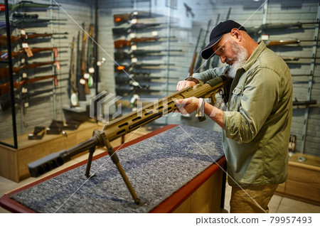 Bearded man reload powerful rifle in gun store Bearded man reload powerful rifle in gun store 79957493