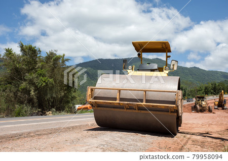 Roller rolling fresh hot asphalt on the new road. Road construction. Roller rolling fresh hot asphalt on the new road. Road construction. 79958094
