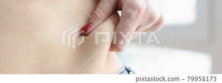 Woman pulling off fold of fat at her waist closeup 79958173