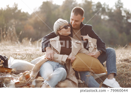 Beautiful couple spend time on a autumn field Beautiful couple spend time on a autumn field 79960044