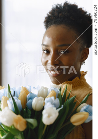 African girl with a bouquet of flowers by window 79960224