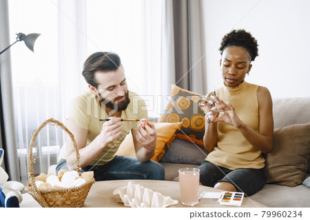 African woman and caucasian man paint easter eggs 79960234