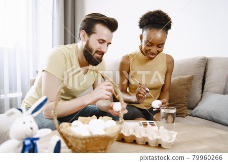 African woman and caucasian man paint easter eggs 79960266