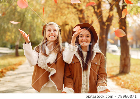 Elegant and stylish girls in a autumn park Elegant and stylish girls in a autumn park 79960871