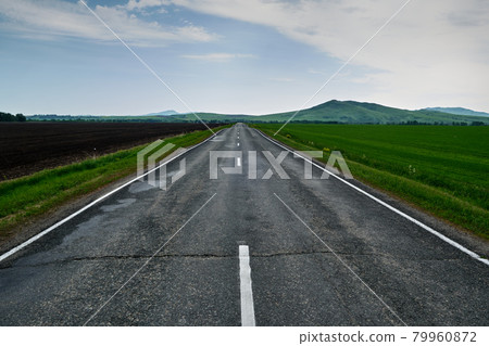 The road leading into the distance to the mountains after the rain. The road leading into the distance to the mountains after the rain. 79960872