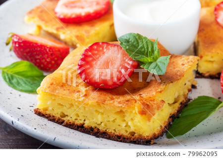 Cottage cheese casserole with strawberries and mint. Delicious homemade dessert made of curd and fresh berries with cream. close up Cottage cheese casserole with strawberries and mint. Delicious homemade dessert made of curd and fresh berries with cream. close up 79962095