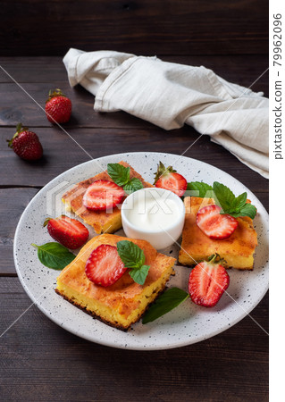 Cottage cheese casserole with strawberries and mint. Delicious homemade dessert made of curd and fresh berries with cream. dark wooden background, copy space. Cottage cheese casserole with strawberries and mint. Delicious homemade dessert made of curd and fresh berries with cream. dark wooden background, copy space. 79962096