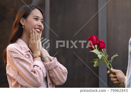 asian teenager woman surprised and smiling at boyfriend gives red rose flowers at dinner in valentine day. young happy couple love and romantic at first date. 79962843