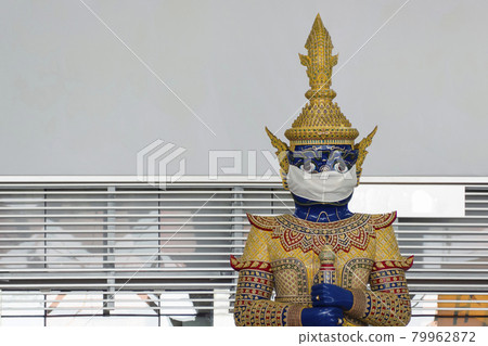 thai traditional giant statue at Suvarnabhumi airport wears protective face mask to encourage mask wearing and the observation of social distancing to prevent infection of covid-19 or coronavirus. thai traditional giant statue at Suvarnabhumi airport wears protective face mask to encourage mask wearing and the observation of social distancing to prevent infection of covid-19 or coronavirus. 79962872