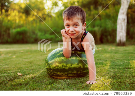 portrait of happy child boy with a large whole watermelon in the back yard 79963389