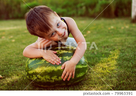 portrait of happy child boy with a large whole watermelon in the back yard 79963391