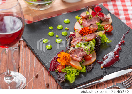 Tasty sliced roast duck breast with fresh vegetable salad closeup on a plate. Tasty sliced roast duck breast with fresh vegetable salad closeup on a plate. 79965280