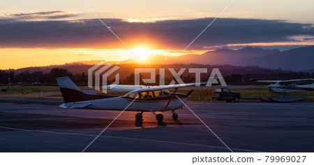 Airplanes parked at an Airport during a colorful summer sunset. 79969027