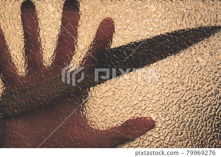 Knife in hand. Aggressive tin attack. Hacking attempt. The criminal behind the glass. Agony crooked hand. Criminal and victim, resisting the hands of the victim and attacking hand with a knife Knife in hand. Aggressive tin attack. Hacking attempt. The criminal behind the glass. Agony crooked hand. Criminal and victim, resisting the hands of the victim and attacking hand with a knife 79969276