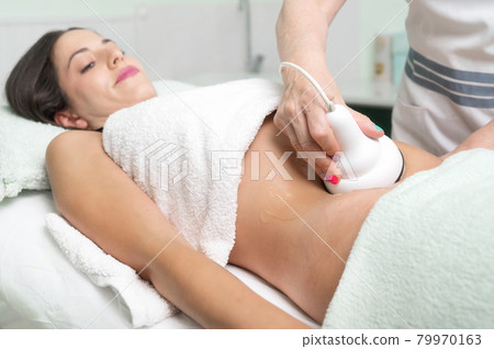 Woman getting ultrasound cavitation treatment by cosmetologist. female client enjoying anti 79970163