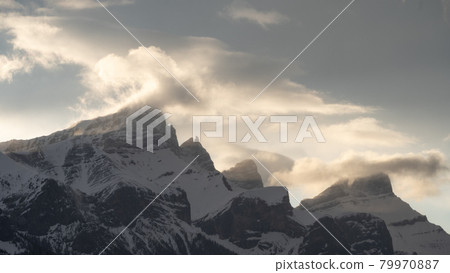 Mountain range shrouded by clouds catching beautiful light, shot during sunset at Canmore, Alberta, Canada 79970887