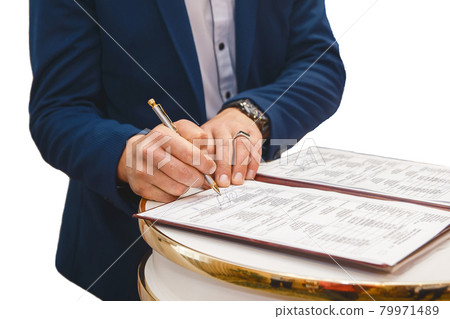 Groom's man's hands put on the signature in the magazine about consent to marriage at the wedding Groom's man's hands put on the signature in the magazine about consent to marriage at the wedding 79971489