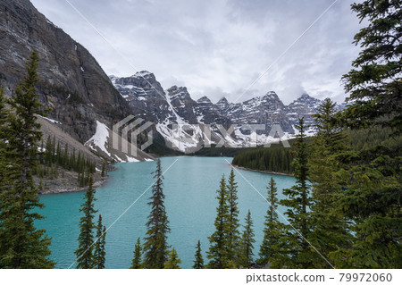 View on beautiful alpine lake with turquoise waters surrounded by magnificent peaks, high perspective shot made on a overcast day at Moraine Lake 79972060