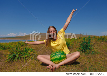 a girl sits on the beach and holds a watermelon. ripening of summer berries Joyful emotions and mood. Summer picnic. a girl sits on the beach and holds a watermelon. ripening of summer berries Joyful emotions and mood. Summer picnic. 80005542
