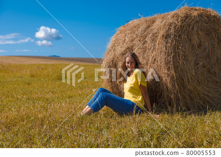 a girl is sunbathing in the hay. village life: harvesting hay for the winter. animal feed. 80005553