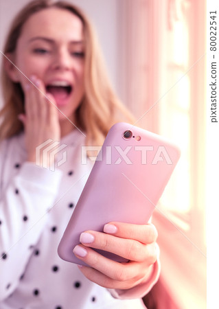 Blonde young girl taking selfie. Video call. Online education. Work from home. Woman holding smartphone. Phone call. Recording new vlog for her channel. Blogger surprised 80022541