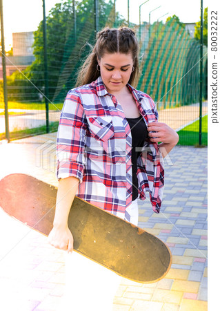 Cute millennial woman smile happy walking down the street with her skateboard. sun backlight and freedom rebel independent concept. Spending day for active board hobby 80032222