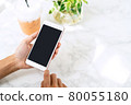 Young woman holding and using smart phone in coffe shop 80055180