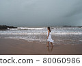 Young woman feeling lonely and sad looking at the sea on a gloomy day 80060986